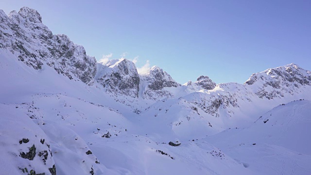 在寒冷的阳光明媚的天气里，滑雪游览覆盖在雪中的岩石山脉景观视频素材