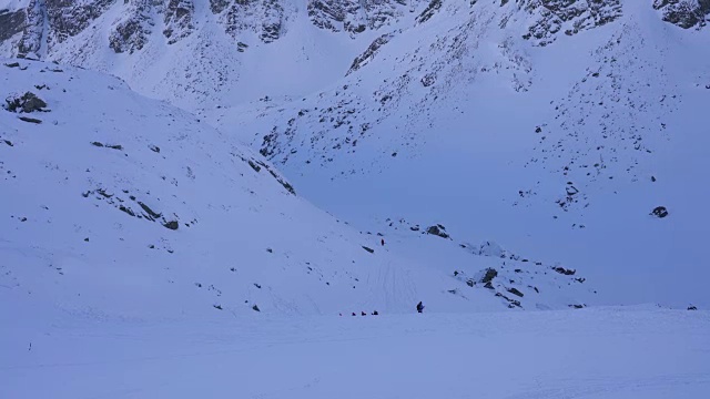 在寒冷的阳光明媚的天气里，滑雪游览覆盖在雪中的岩石山脉景观视频素材