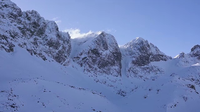 在寒冷的阳光明媚的天气里，滑雪游览覆盖在雪中的岩石山脉景观视频素材