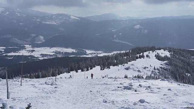 在寒冷的阳光明媚的天气里，滑雪游览覆盖在雪中的岩石山脉景观视频素材