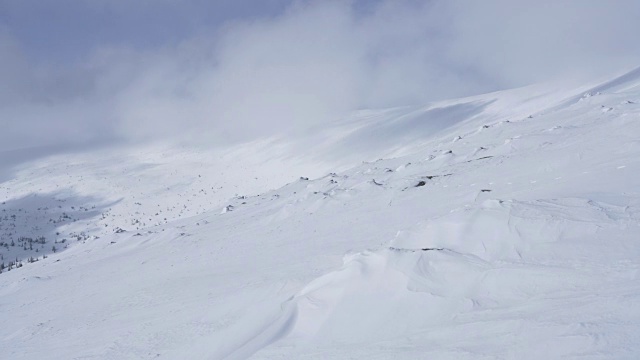 在寒冷的阳光明媚的天气里，滑雪游览覆盖在雪中的岩石山脉景观视频素材