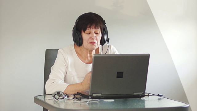 一位中年妇女通过Skype与家人联系。视频连接。挥手，说再见，结束谈话视频素材