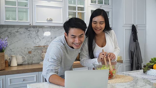 这对夫妇正在用笔记本电脑愉快地一起做饭视频素材