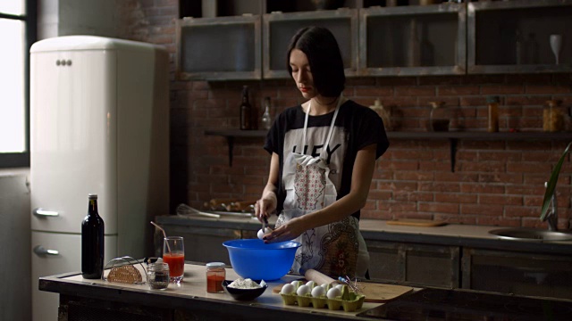 在厨房里把鸡蛋打到碗里的时髦女人视频素材