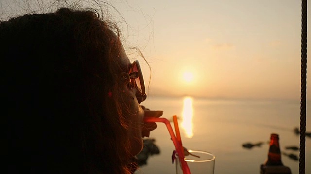 年轻漂亮的女人在太阳眼镜享受热带龙舌兰日出酒精鸡尾酒装饰在海边在惊人的日落在她的暑假。缓慢的运动。1920 x1080视频素材