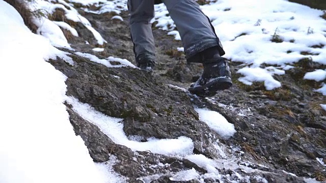 清晨，一个面目全非的人爬上了山道。年轻的男游客走在雪山上。健康积极的生活方式。假日或假期的概念。后视图慢动作视频素材