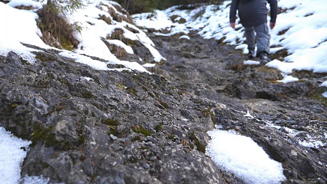 清晨在雪山上行走的男游客的后视图。在旅途中，一个面目全非的人爬上了山路。健康积极的生活方式。假期的概念。慢动作视频素材