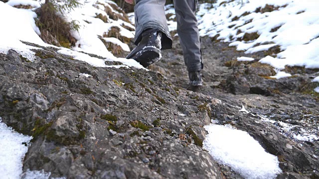 清晨，一个面目全非的人爬上了山道。年轻的男游客走在雪山上。健康积极的生活方式。假日或假期的概念。后视图慢动作视频素材