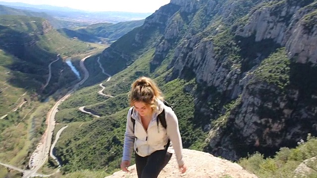 年轻女子爬过山谷，进入山脉视频素材