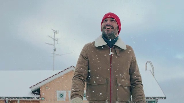 一个美丽的冬日，一个英俊的男人走在后院的肖像。软雪落。视频素材