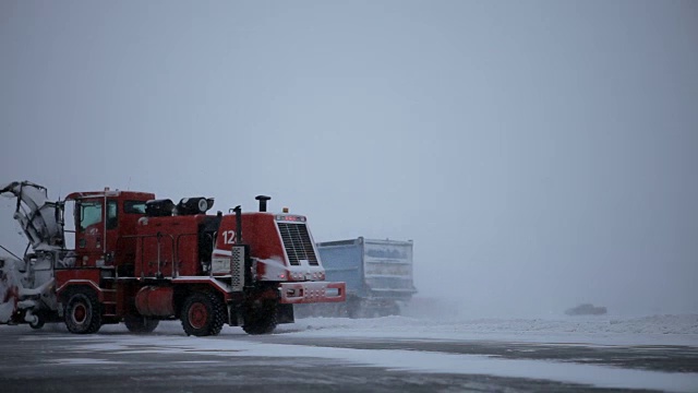 扫雪机在下雪时清理飞机跑道视频素材