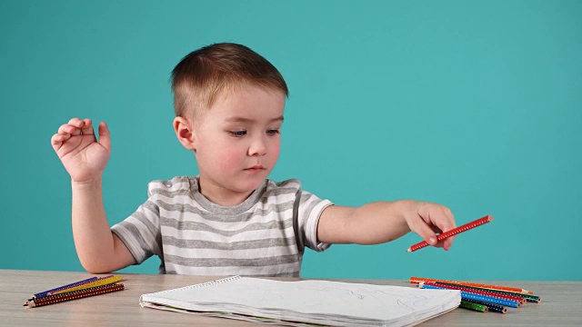 启发小男孩在桌子上用铅笔画画，孤立在蓝色视频素材