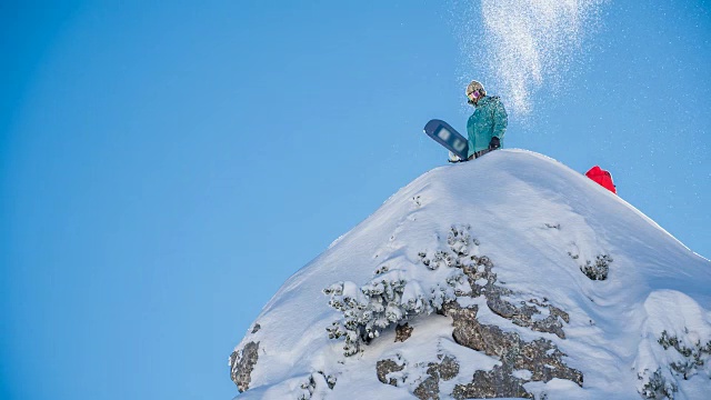 滑雪者站在雪山顶上，向空中抛雪视频素材