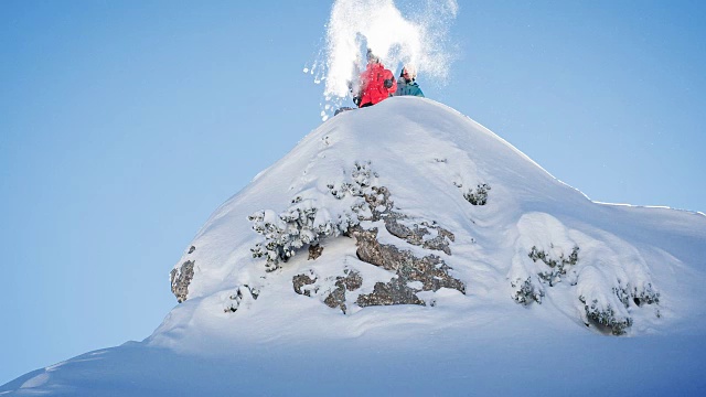 滑雪者站在雪山顶上，向空中抛雪视频素材