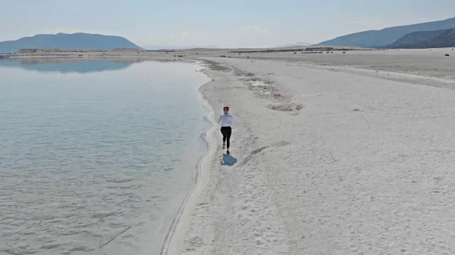 在土耳其萨尔达湖海滩上跑步的女人视频素材