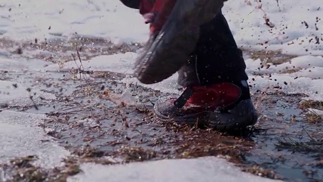 徒步者穿着靴子跑步，在雪和水里溅水，超级慢的动作视频素材