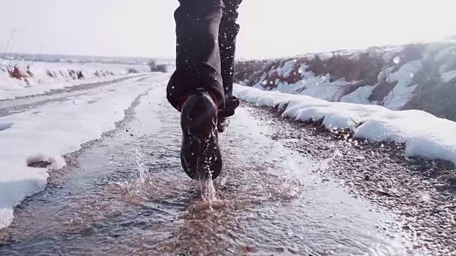 徒步者穿着靴子跑步，在雪地上溅水，超级慢动作视频素材