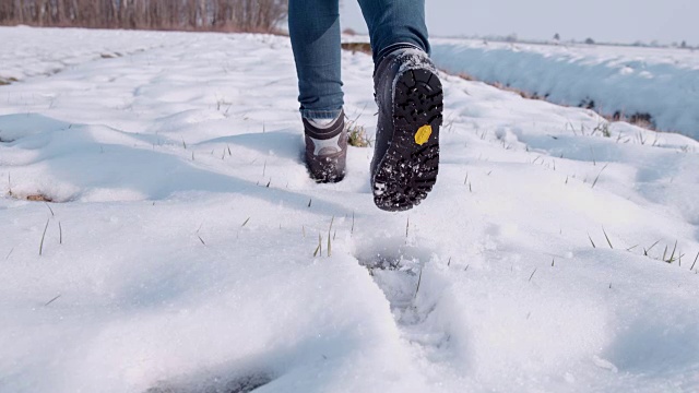 徒步旅行者穿着靴子在阳光明媚的雪地里行走，超级慢动作视频素材