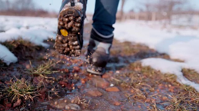 徒步者穿着靴子走在雪地里的水里，超级慢动作视频素材