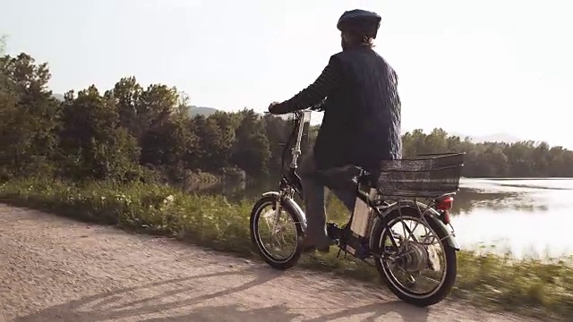 湖边骑电动自行车的老太太视频素材