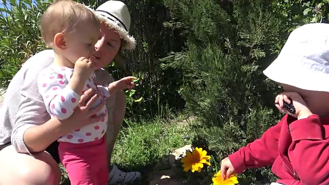 孩子们和妈妈在花园里闻着花香视频素材