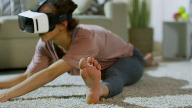 戴着VR眼镜做劈叉的女人视频素材画面2