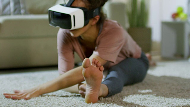 戴着VR眼镜做劈叉的女人视频素材画面4