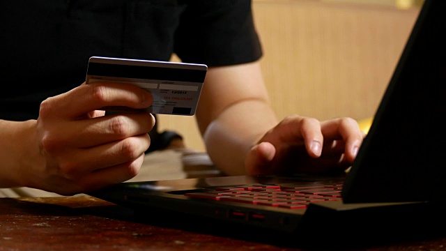摄影:男人手持信用卡，用笔记本电脑进行网上购物——经营理念视频素材画面4