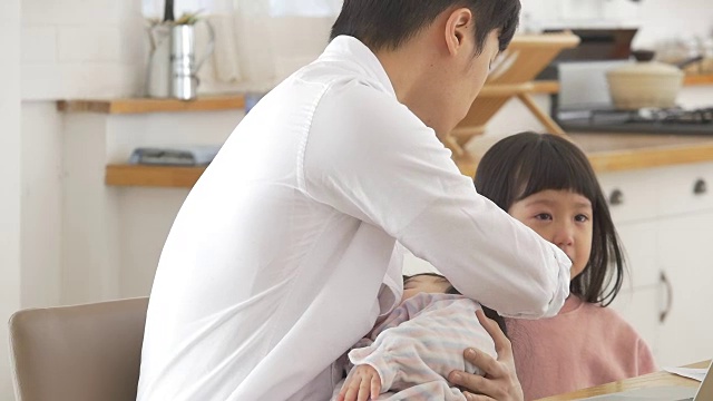一位韩国父亲抱着一个婴儿试图安慰他哭泣的女儿视频素材画面2