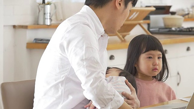 一位韩国父亲抱着一个婴儿试图安慰他哭泣的女儿视频素材画面3
