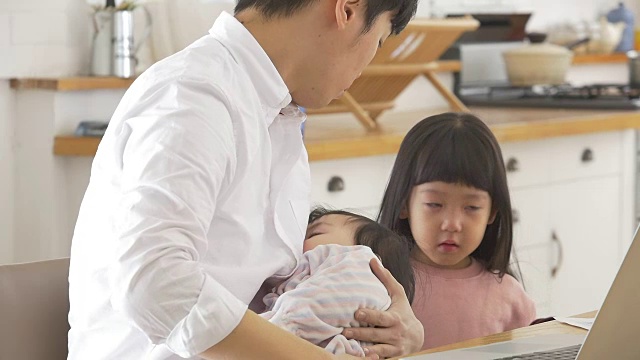 一位韩国父亲抱着一个婴儿试图安慰他哭泣的女儿视频素材画面1
