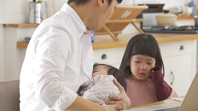 一位韩国父亲抱着一个婴儿试图安慰他哭泣的女儿视频素材画面2