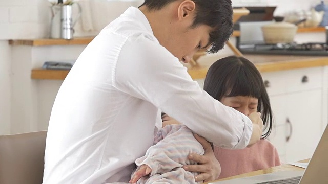 一位韩国父亲抱着一个婴儿试图安慰他哭泣的女儿视频素材画面4