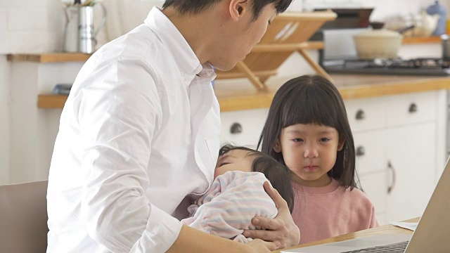 一位韩国父亲抱着一个婴儿试图安慰他哭泣的女儿视频素材画面1