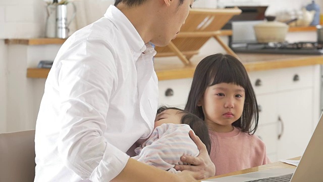 一位韩国父亲抱着一个婴儿试图安慰他哭泣的女儿视频素材画面2