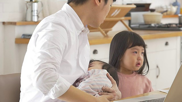 一位韩国父亲抱着一个婴儿试图安慰他哭泣的女儿视频素材画面4