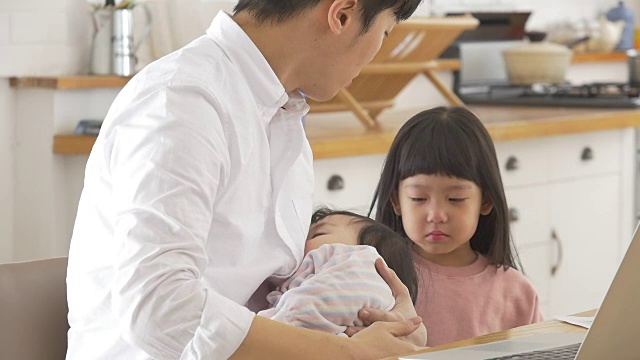 一位韩国父亲抱着一个婴儿试图安慰他哭泣的女儿视频素材画面1