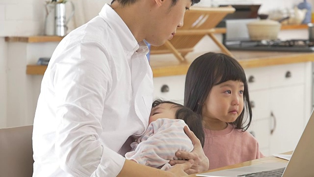 一位韩国父亲抱着一个婴儿试图安慰他哭泣的女儿视频素材画面2