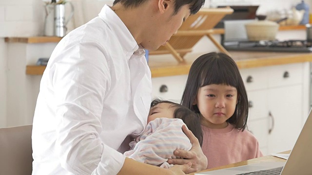 一位韩国父亲抱着一个婴儿试图安慰他哭泣的女儿视频素材画面4