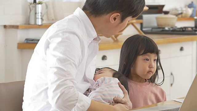 一位韩国父亲抱着一个婴儿试图安慰他哭泣的女儿视频素材画面1