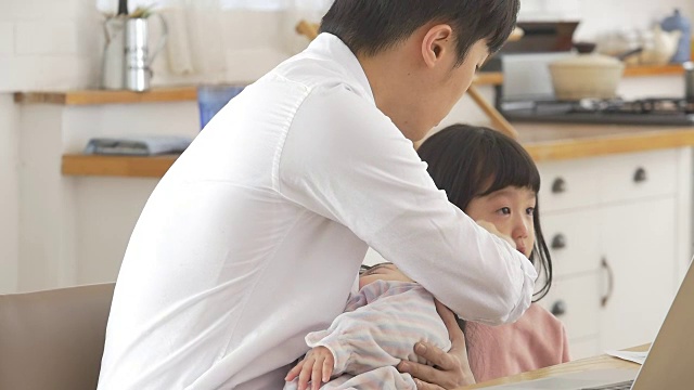 一位韩国父亲抱着一个婴儿试图安慰他哭泣的女儿视频素材画面2