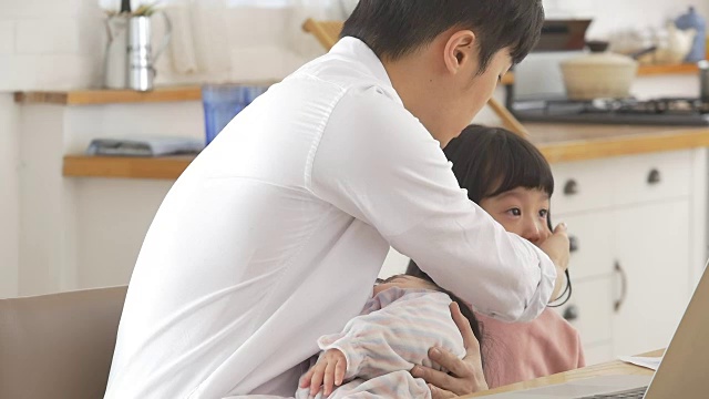 一位韩国父亲抱着一个婴儿试图安慰他哭泣的女儿视频素材画面3