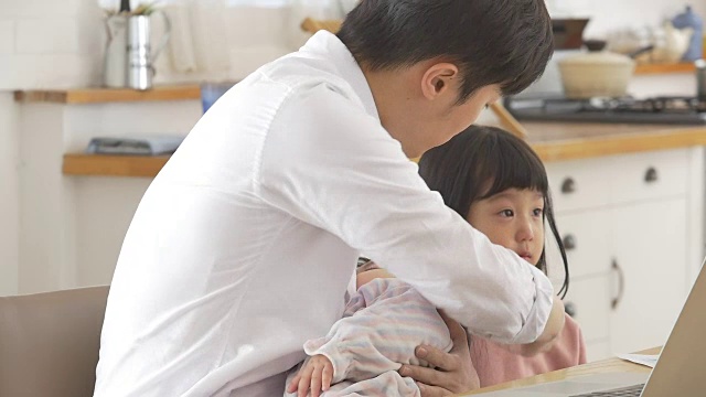 一位韩国父亲抱着一个婴儿试图安慰他哭泣的女儿视频素材画面4