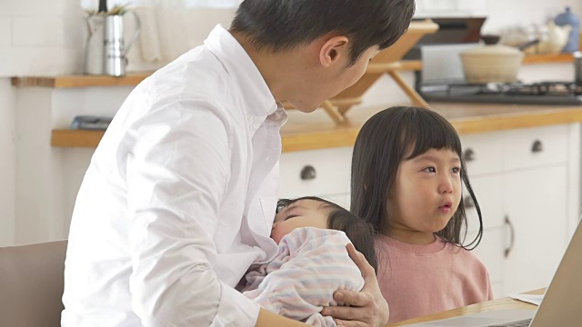 一位韩国父亲抱着一个婴儿试图安慰他哭泣的女儿视频素材画面1