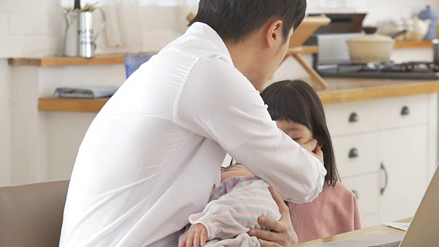 一位韩国父亲抱着一个婴儿试图安慰他哭泣的女儿视频素材画面3