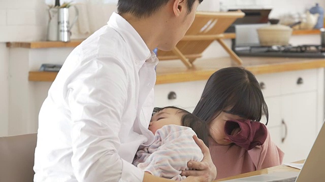 一位韩国父亲抱着一个婴儿试图安慰他哭泣的女儿视频素材画面1