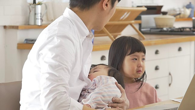 一位韩国父亲抱着一个婴儿试图安慰他哭泣的女儿视频素材画面2