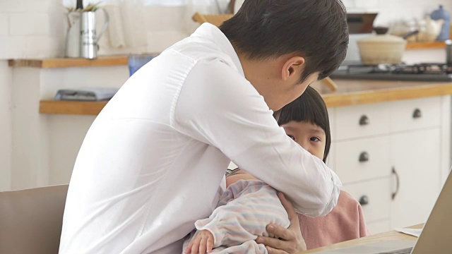 一位韩国父亲抱着一个婴儿试图安慰他哭泣的女儿视频素材画面4