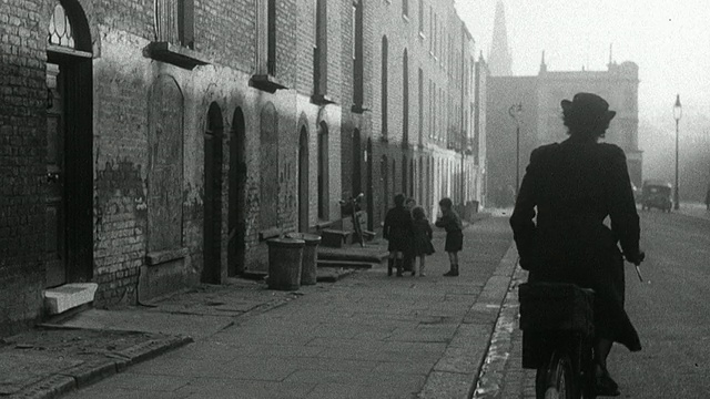 1952年，英国，Wadhurst，蒙太奇区护士从公寓里出来，把医疗包绑到自行车上，骑着车走过街道，路过在人行道上玩耍的孩子们视频素材画面1