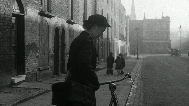 1952年，英国，Wadhurst，蒙太奇区护士从公寓里出来，把医疗包绑到自行车上，骑着车走过街道，路过在人行道上玩耍的孩子们视频素材画面3